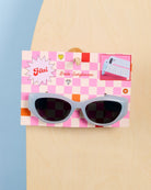 Checkered sunglasses with a pink packaging box on a beige and blue background