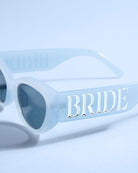 Light blue sunglasses with 'BRIDE' text on a light blue background