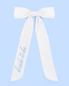 White sash with 'bride to be' text on a light blue background