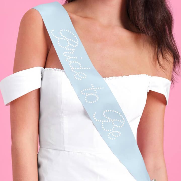 Person wearing a 'Miss America' sash on a pink background