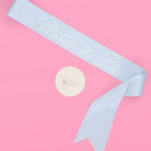 Baby shower sash with 'Daddy to be' text on a pink background