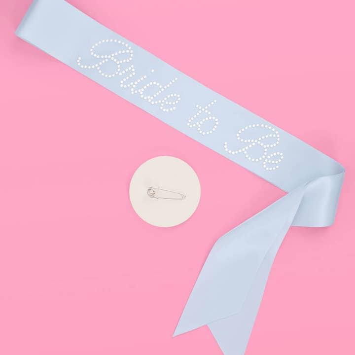 Baby shower sash with 'Daddy to be' text on a pink background