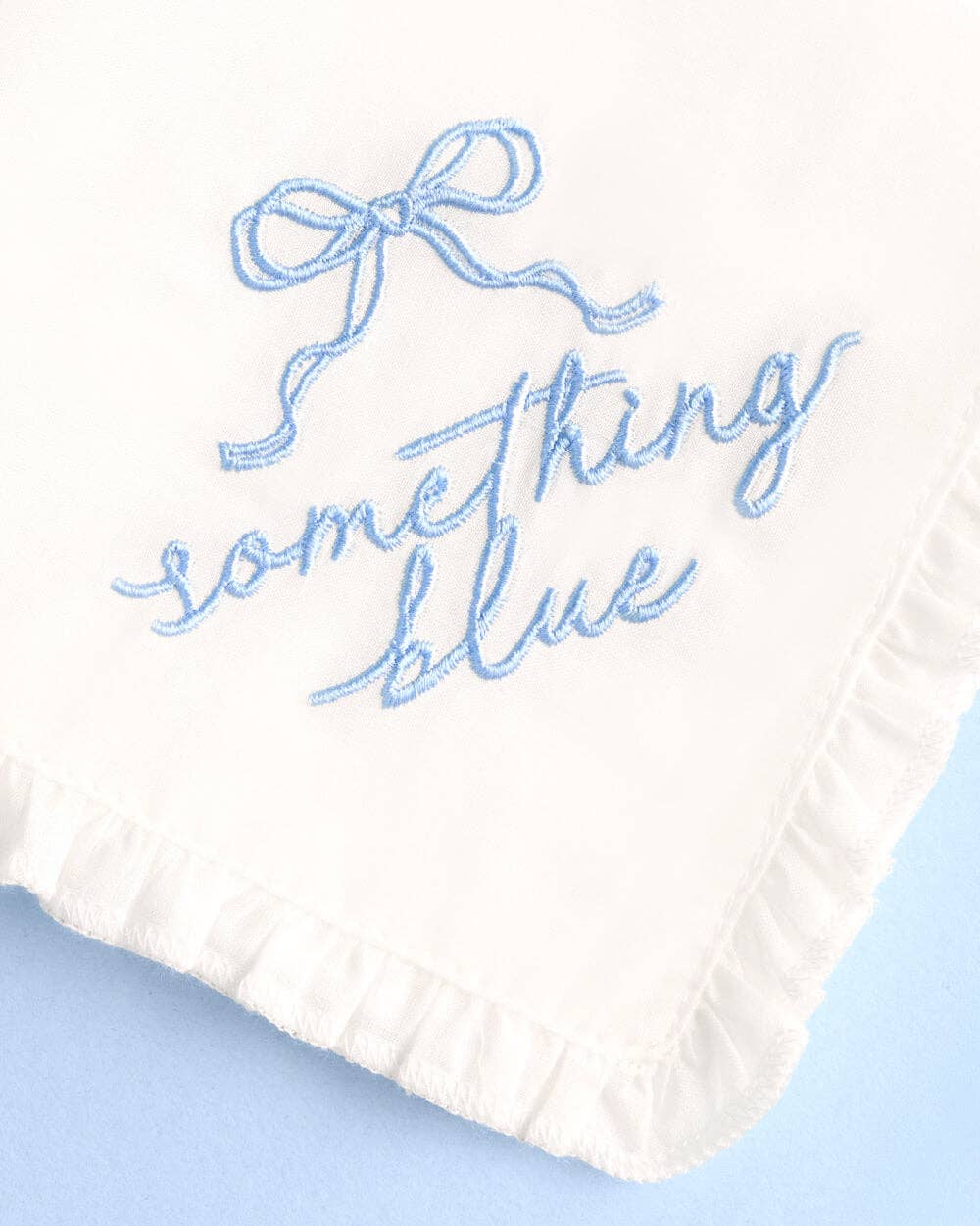 White fabric with blue embroidered text on a light blue background