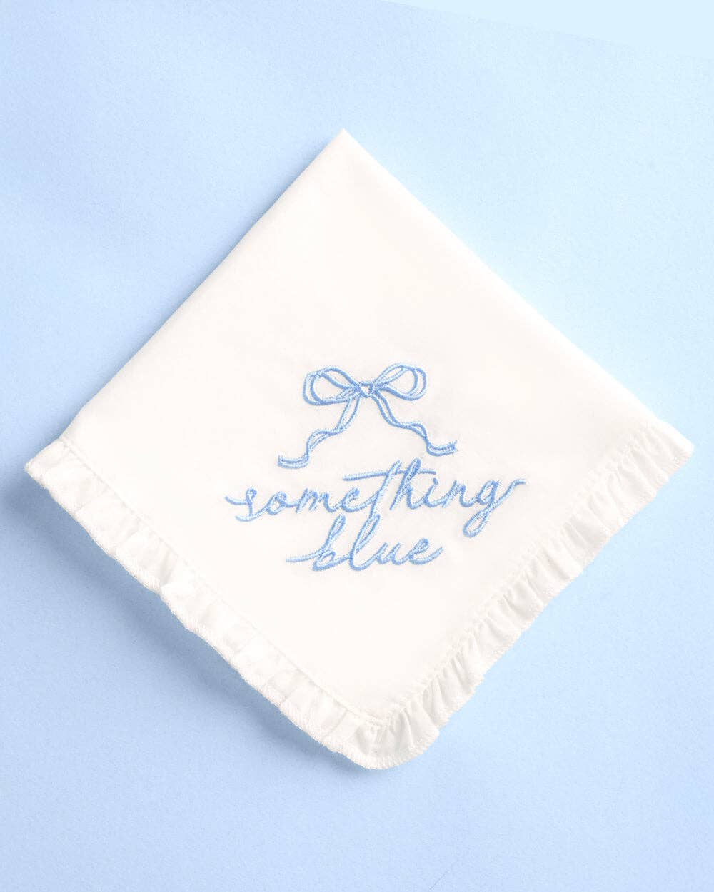 White handkerchief with 'something blue' embroidery on a light blue background
