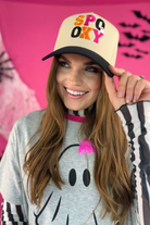 a classic black and cream adjustable canvas trucker hat with a cream structured front, a curved bill, and a snapback closure, finished with multicolor embroidered 'SPOOKY' lettering in black, orange, and pink, plus playful white embroidered mini bat, ghost, and spider accents