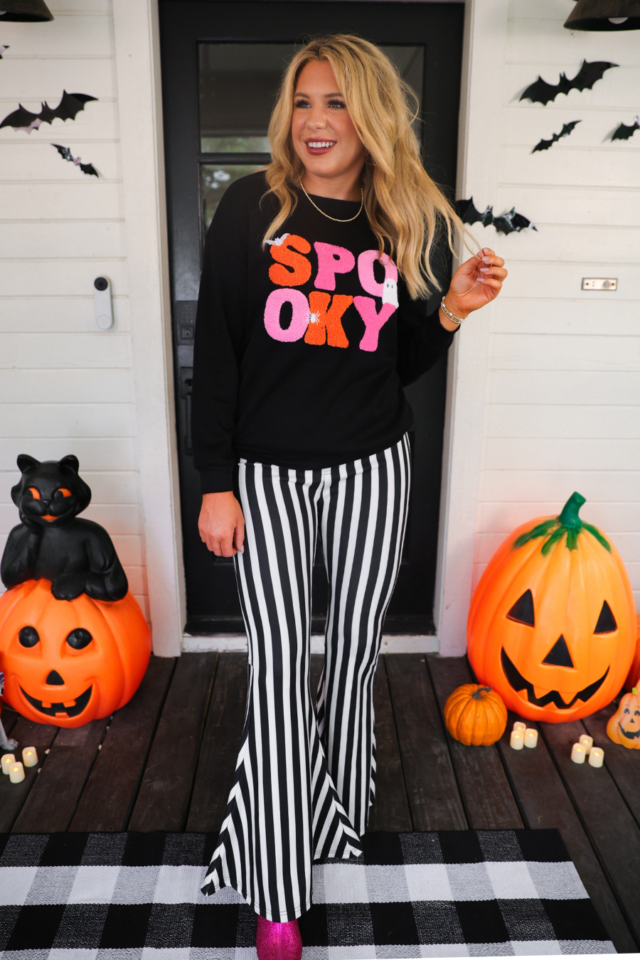 a black long-sleeve pullover made of ultra soft luxe material with bold plush chenille 'SPOOKY' patch lettering (orange and pink), white embroidered character accents (tiny bat, ghost and spider), ribbed cuffs, a banded hem, and a relaxed fit for a classic silhouette