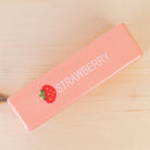 a 4oz strawberry butter-stick inspired foam fidget toy made from slow-rise polyurethane (PU) foam with a soft texture, pastel pink design, a tiny strawberry accent detail, playful printed lettering, and individual packaging