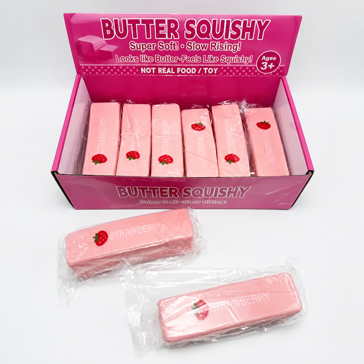 A pink display box labeled 'BUTTER SQUISHY' containing several strawberry-themed squishy bars, with two individually wrapped squishy bars placed in front on a white background.