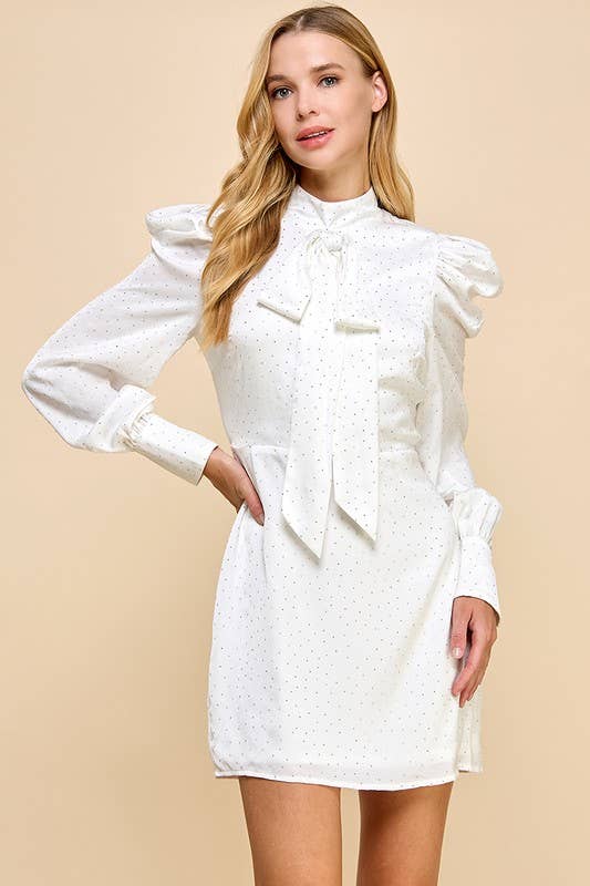 a white lined studded sheath dress with a high neckline accented with a decorative bow, puff shoulders, long cuffed sleeves, and a hidden rear zipper