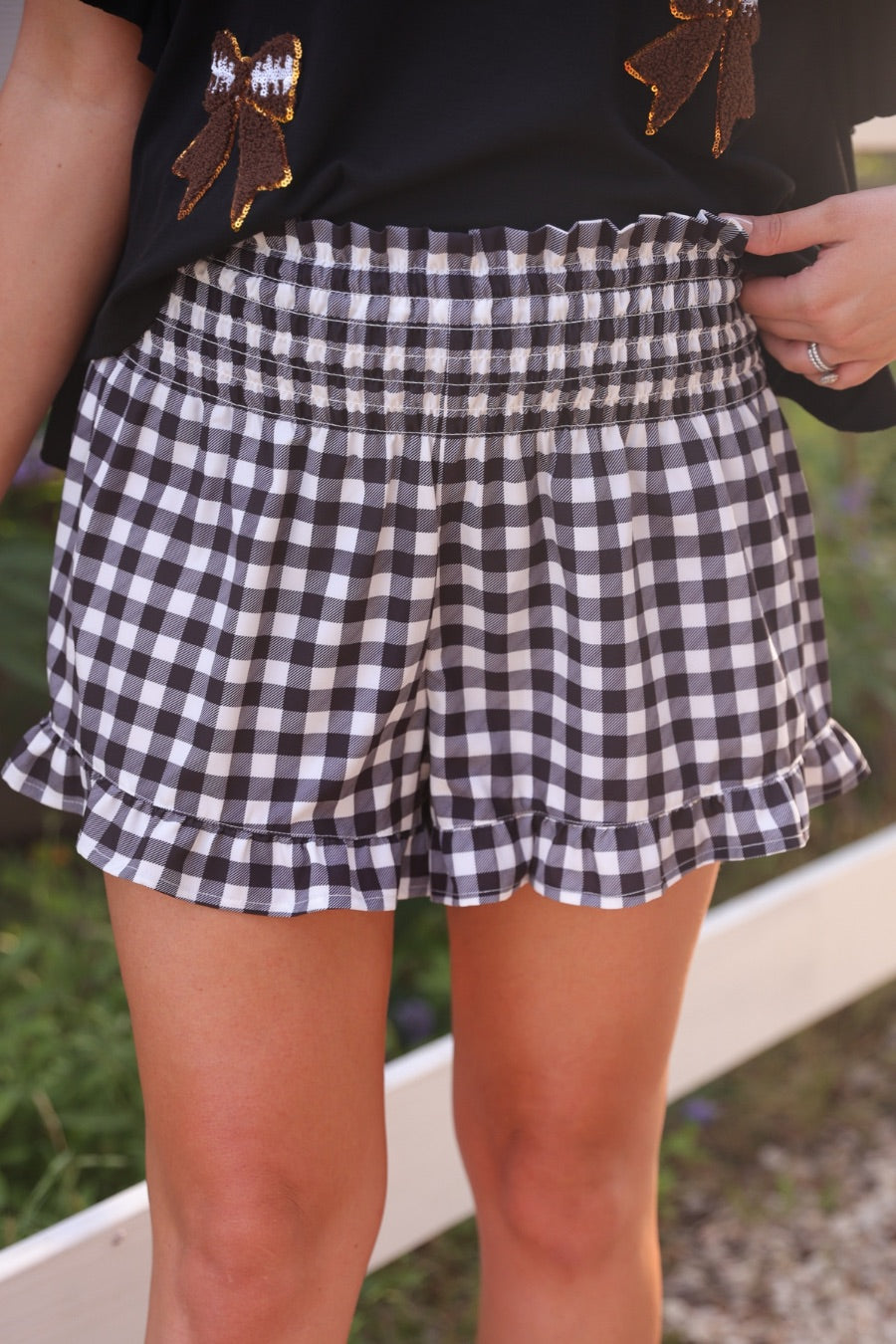 high-waisted gingham shorts with smocked waistband and ruffle hem in black