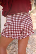 high-waisted gingham shorts with smocked waistband and ruffle hem in maroon