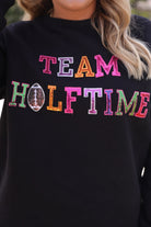 black long-sleeve sweatshirt made from soft mid-weight fabric with a crew neckline, straight hem, and bold multicolored varsity-style chenille patches that spell out 'TEAM HALFTIME' across the front chest