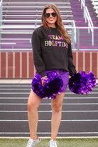 black long sleeve sweatshirt made from a midweight, soft material fabric with a crew neckline, straight hemline, and multicolored letter patches spelling out TEAM HALFTIME&nbsp;on the front