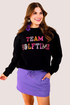 black long-sleeve sweatshirt made from soft mid-weight fabric with a crew neckline, straight hem, and bold multicolored varsity-style chenille patches that spell out 'TEAM HALFTIME' across the front chest