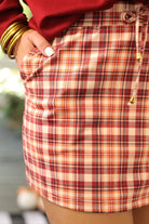 mid-rise relaxed fit everyday skort made of lightweight material with built-in cream shorts, drawstring tie with gold bead accents, an elastic band on the back, and side pockets, designed on a burgundy, ivory, and orange plaid pattern