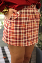 mid-rise relaxed fit everyday skort made of lightweight material with built-in cream shorts, drawstring tie with gold bead accents, an elastic band on the back, and side pockets, designed on a burgundy, ivory, and orange plaid pattern