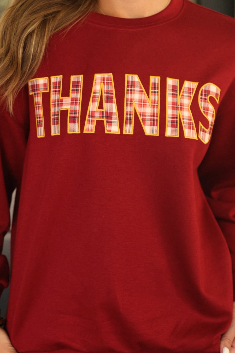 long-sleeve burgundy pullover with plaid 'THANKS' letters outlined in embroidery on a soft fabric