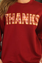 long-sleeve burgundy pullover with plaid 'THANKS' letters outlined in embroidery on a soft fabric