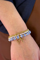 three-piece bracelet set with a charming mix of brass, sheer pearls, floral-patterned beads, and a dainty bow accent