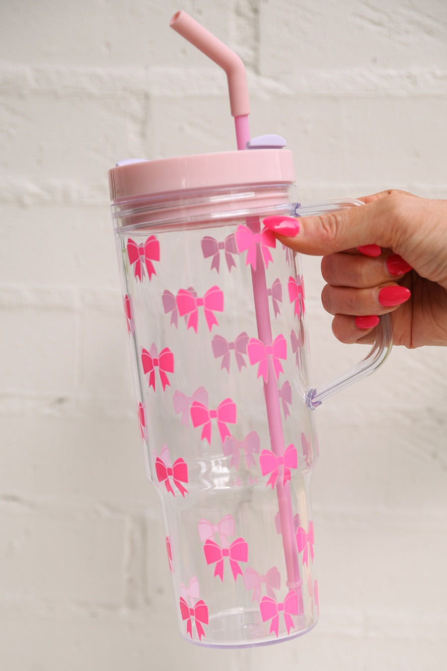 40-ounce pink bow acrylic tumbler with a reusable straw (pink), flexible mouthpiece (pastel pink), handle, screw-on lid (pastel pink with a lavender rotate lid tab), and car cup holder compatible