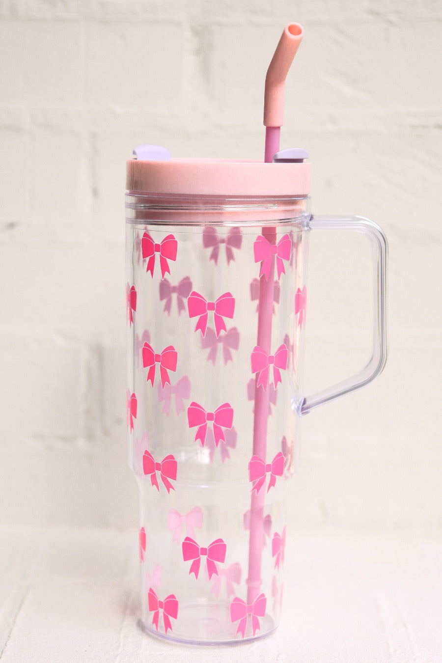 40-ounce pink bow acrylic tumbler with a reusable straw (pink), flexible mouthpiece (pastel pink), handle, screw-on lid (pastel pink with a lavender rotate lid tab), and car cup holder compatible
