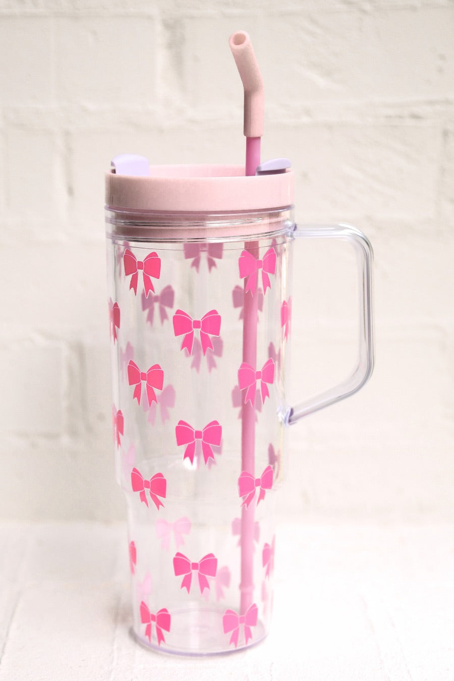 40-ounce pink bow acrylic tumbler with a reusable straw (pink), flexible mouthpiece (pastel pink), handle, screw-on lid (pastel pink with a lavender rotate lid tab), and car cup holder compatible