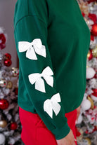 a rich green long-sleeve pullover accented with satin bows cascading down each sleeve