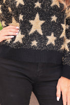 a black long-sleeve crewneck sweater with a festive star motif, shimmering tinsel woven throughout, and ribbed trim at the neckline, cuffs, and hemline