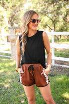 mid-rise relaxed fit activewear shorts with side pockets and a tie waist drawstring with gold bead accent, designed with a football-lace inspired pattern print fabric down each leg, brown base, and black trim
