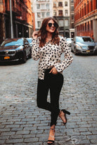 loose long sleeve top made with lightweight material with a button-up front closure, a collared neckline, an accent chest pocket, and a relaxed silhouette that falls into a rounded hemline on a neutral leopard print fabric