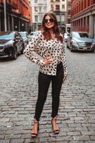 loose long sleeve top made with lightweight material with a button-up front closure, a collared neckline, an accent chest pocket, and a relaxed silhouette that falls into a rounded hemline on a neutral leopard print fabric