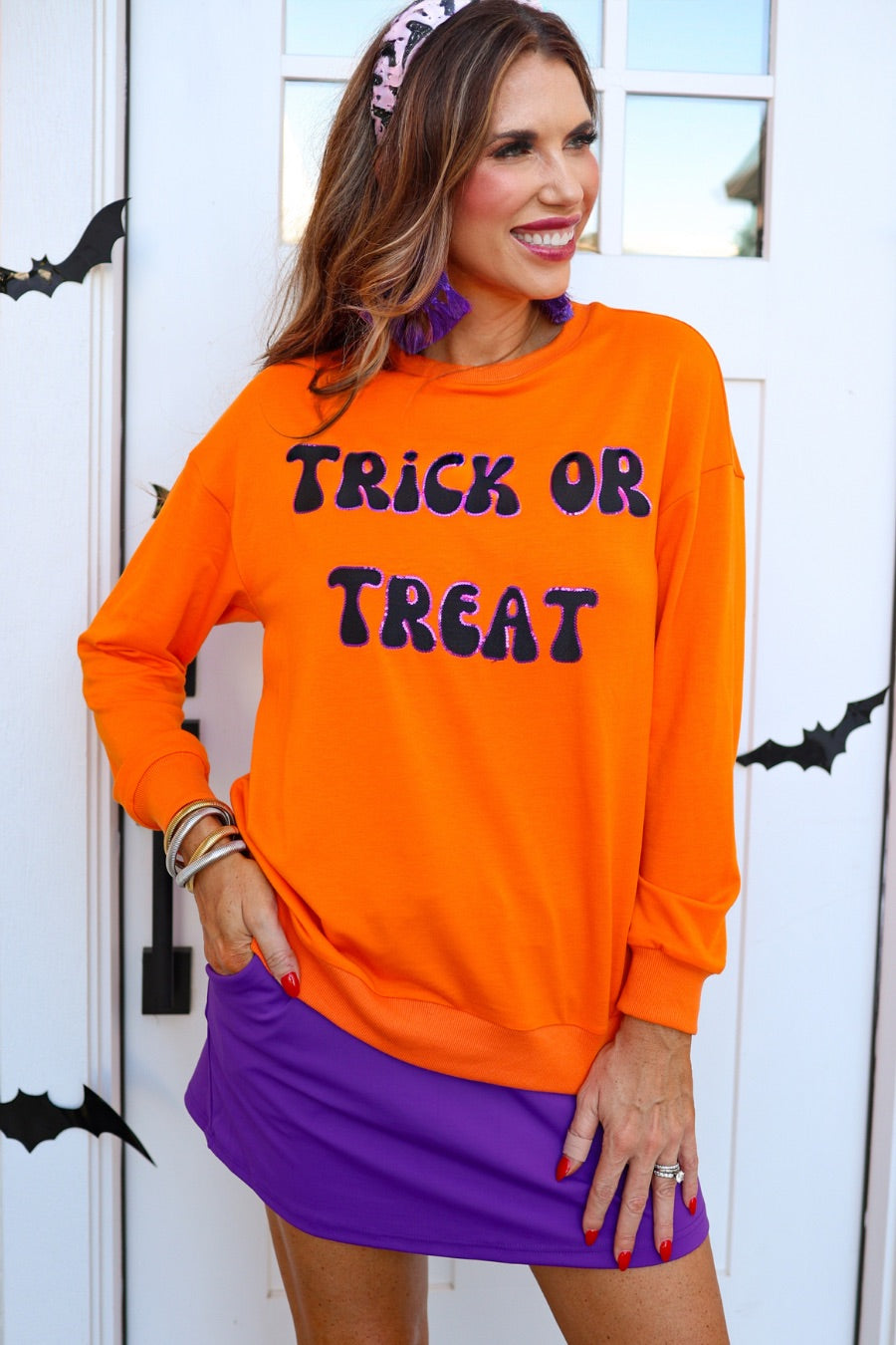 a long-sleeve sweatshirt with plush black embroidered 'TRICK OR TREAT' appliqué lettering, purple sequin outlining, crew neckline, ribbed cuffs, a banded hem, and a relaxed fit for a classic silhouette