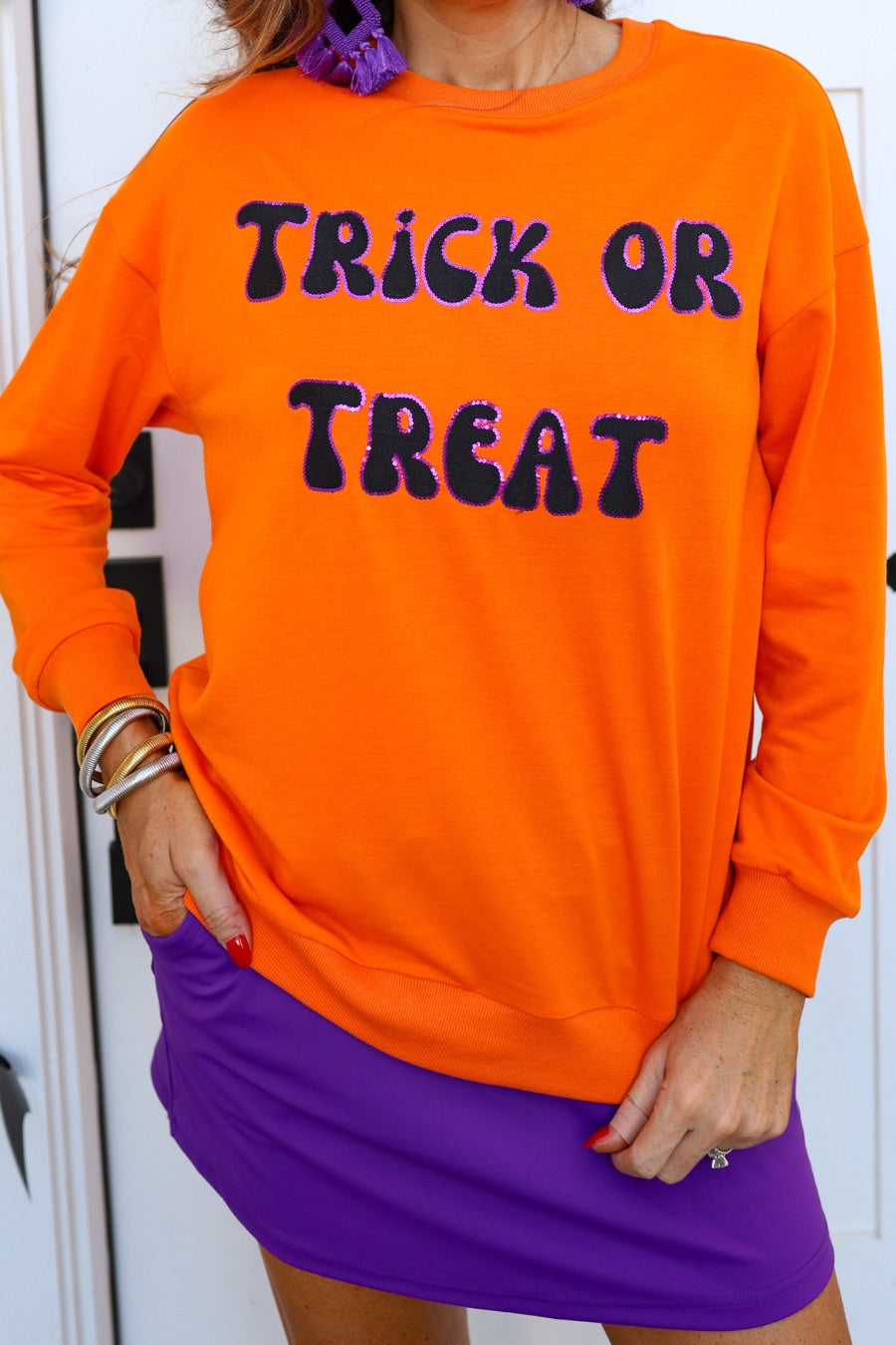 a long-sleeve sweatshirt with plush black embroidered 'TRICK OR TREAT' appliqué lettering, purple sequin outlining, crew neckline, ribbed cuffs, a banded hem, and a relaxed fit for a classic silhouette