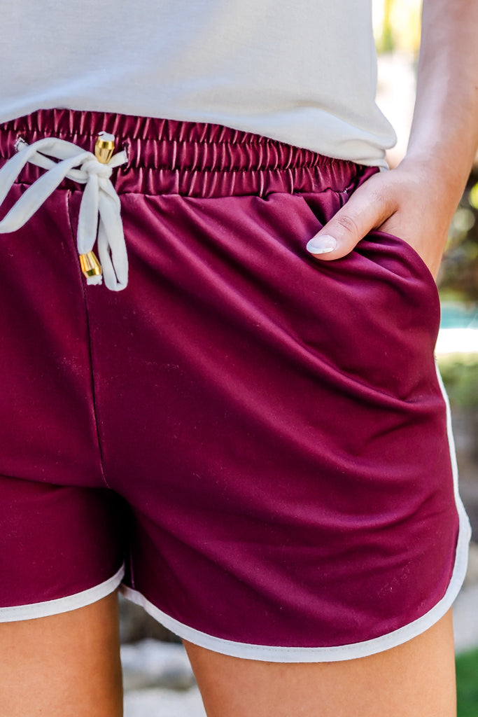 mid-rise, tie waist drawstring, side pockets, & relaxed fit on solid maroon fabric with white piping