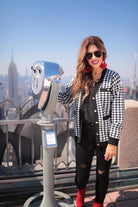 long sleeve jacket with a front gold button closure, contrasting trim on the pockets and edges, pockets (two faux, two functional), and a collared neckline on a black and ivory houndstooth print