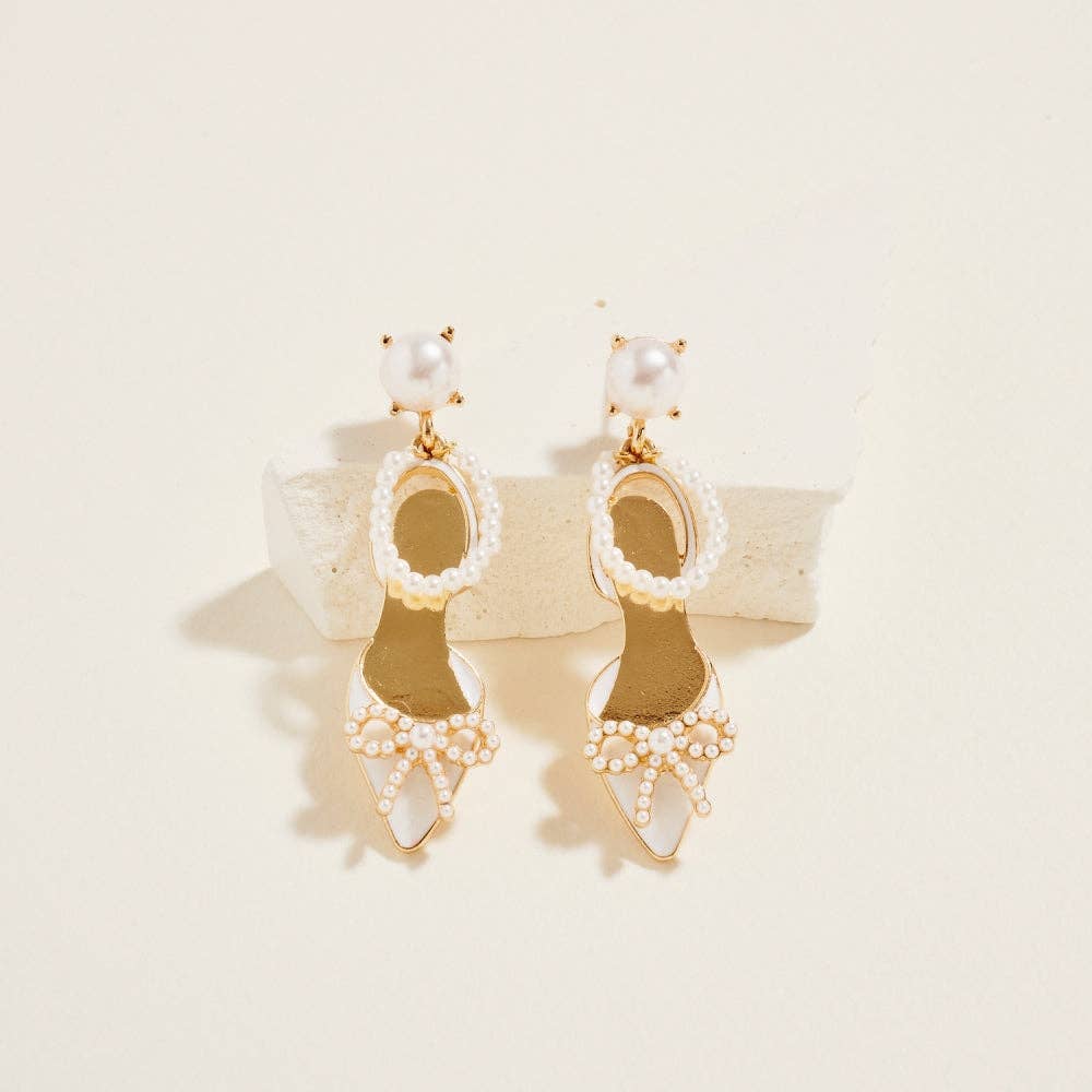 Pair of gold and pearl earrings on a beige background