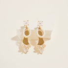 Pair of gold and pearl earrings on a beige background