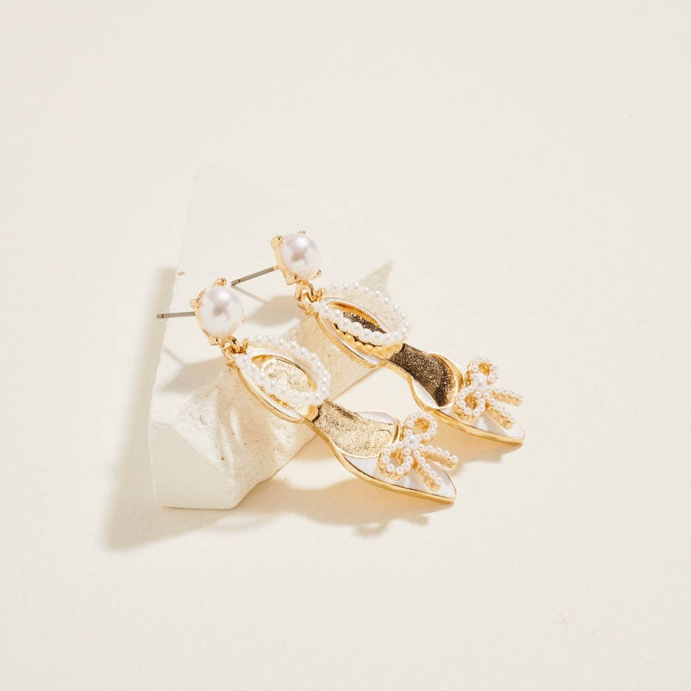 Gold earrings with pearl accents on a beige background