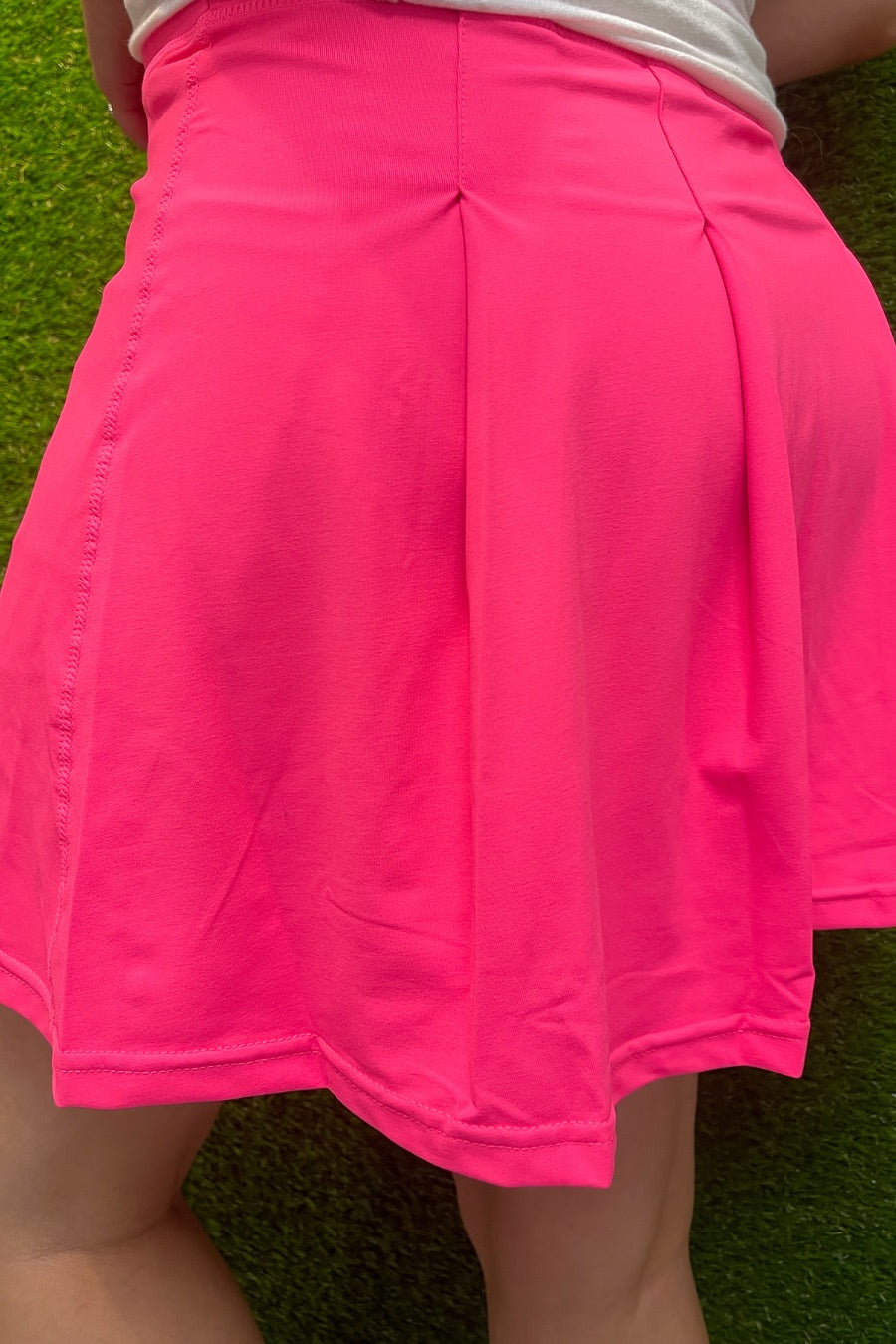 a slimming true to size solid pink skort with built-in shorts, interior side pockets, and a pleated back