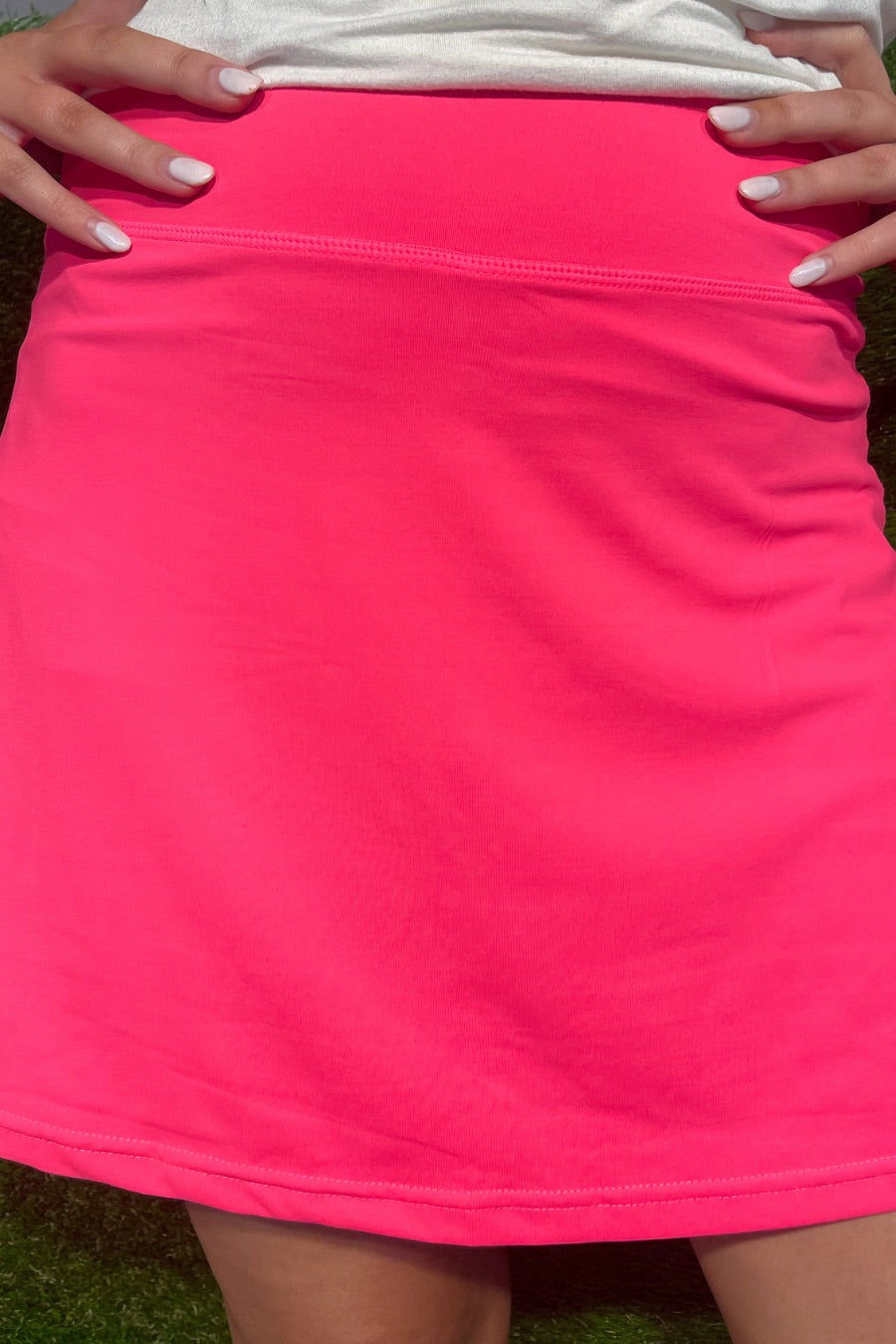 a slimming true to size solid pink skort with built-in shorts, interior side pockets, and a pleated back