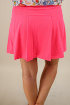 a slimming true to size solid pink skort with built-in shorts, interior side pockets, and a pleated back