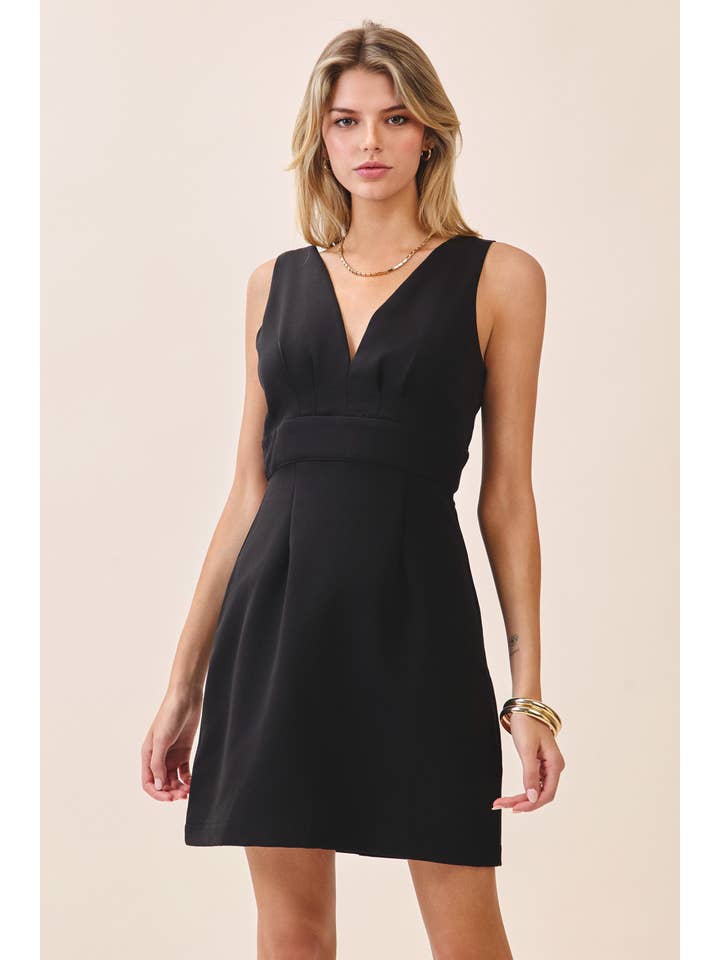 a black sleeveless mini dress with a deep V-neckline, wide waistband, dramatic low back, and self-tie bow detail