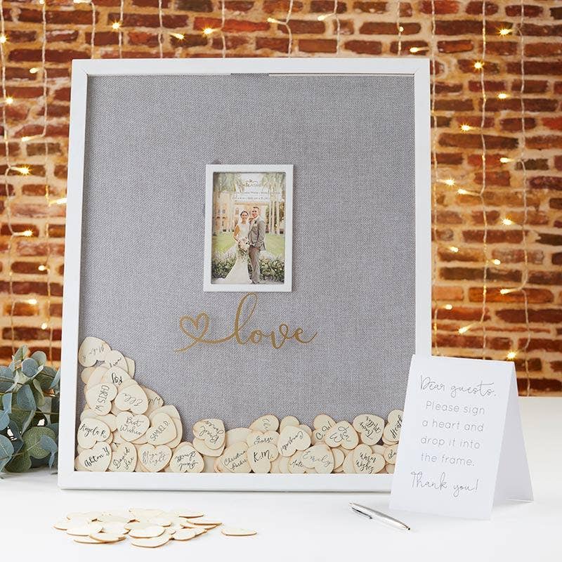 Decorative frame with 'love' text and heart-shaped wooden tokens against a brick wall background.