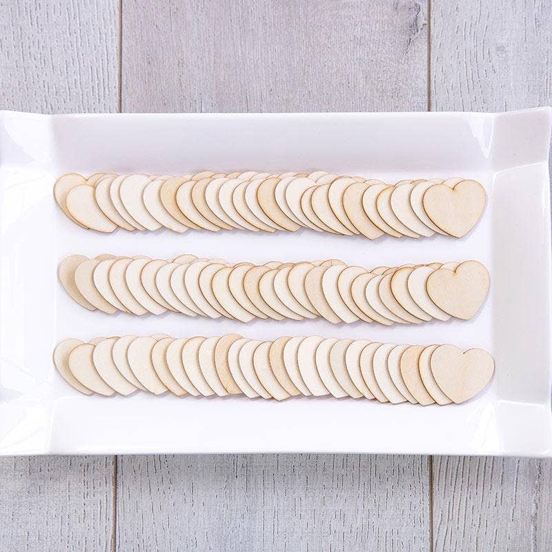 Wooden heart-shaped cutouts on a white paper bag with a wooden surface background