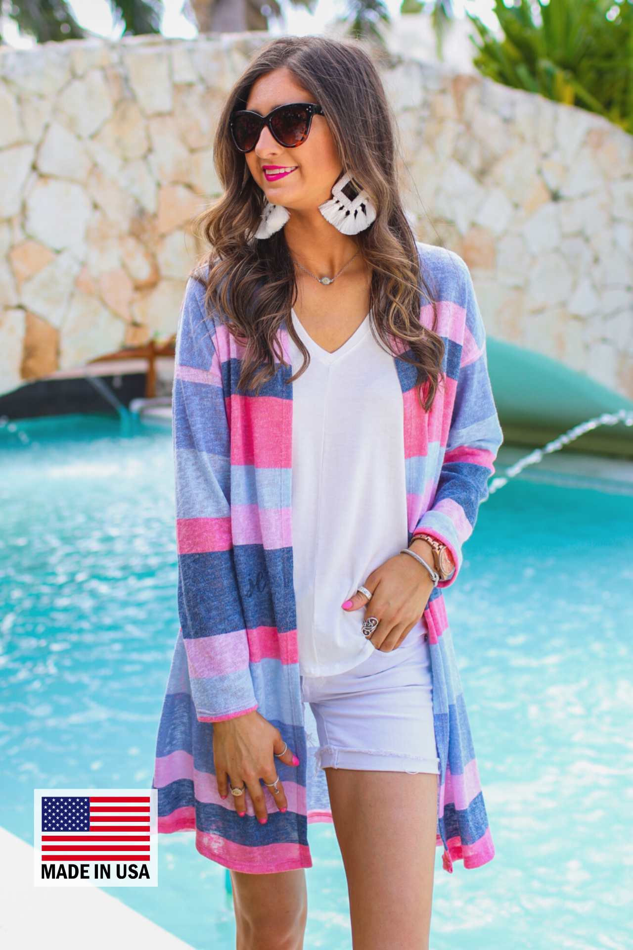 a blue long-sleeve open-front cardigan with a modern drop-shoulder silhouette, bold blue and pink horizontal stripes, and a lightweight relaxed fit, accented with a MADE IN USA watermark in bottom left-hand corner
