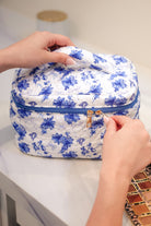 a structured bag with a spacious interior, a secure double zip around closure, a top handle, and gold accents on a quilted body in blue blossom (white/blue)