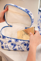 a structured bag with a spacious interior, a secure double zip around closure, a top handle, and gold accents on a quilted body in blue blossom (white/blue)