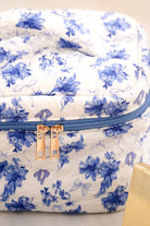 a structured bag with a spacious interior, a secure double zip around closure, a top handle, and gold accents on a quilted body in blue blossom (white/blue)