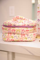 a structured bag with a spacious interior, a secure double zip around closure, a top handle, and gold accents on a quilted body in daylight bow (multi)