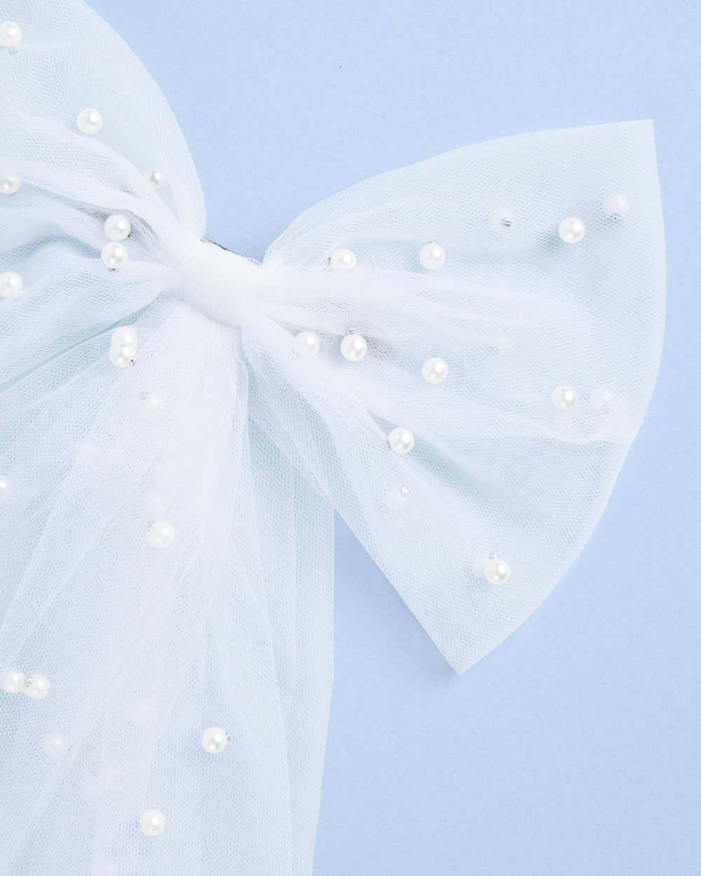 Large white bow with pearl-like embellishments on a light blue background
